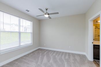 A bedroom with two windows and a ceiling fan